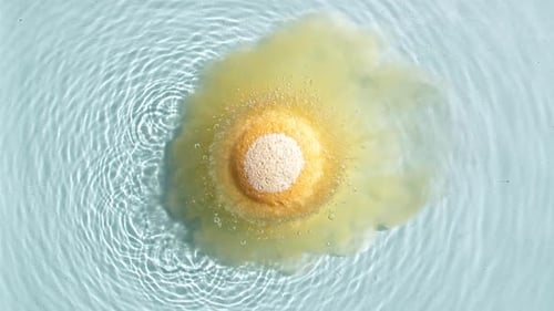 Bath Bomb Dissolving in Water, Releasing Yellow Tint