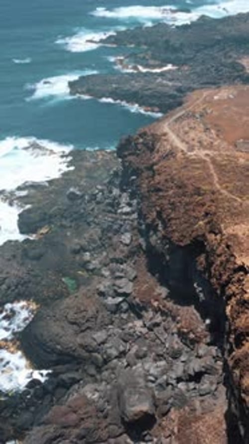 Dramatic Cliffside with Crashing Waves Aerial Shot in Portrait