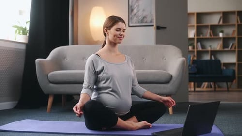 Pregnant Woman Doing Yoga at Home with Laptop