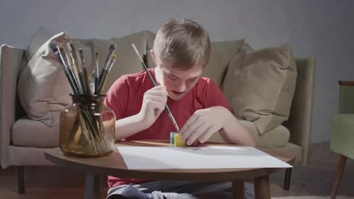 Young Person Painting with Yellow Paintbrush Indoors