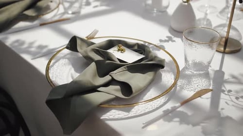 Elegant Table Setting with a White Plate on a White Tablecloth at a Wedding and a Beautiful Green
