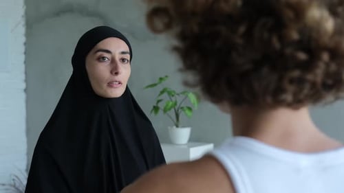 Una mujer musulmana con hiyab le cuenta a una europea las reglas de la sharia
