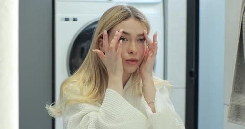 Close Up of Young Woman Looking in Mirror at Perfect Healthy Skin Touching Face with Hands Anti