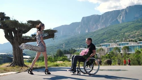 Woman Greets Man in Wheelchair and Kisses Him