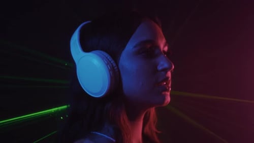 Young Adult Vaping with Headphones in Neon Lighting