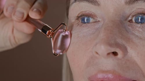 Close Up of Senior Woman Massaging Skin around Eye with Facial Roller