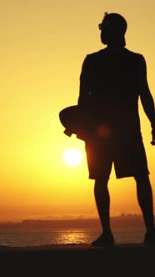 Silhouette of Man with Skateboard at Sunset by Ocean
