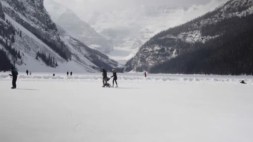 People including couple with a stroller skate on the lake Luise during winter