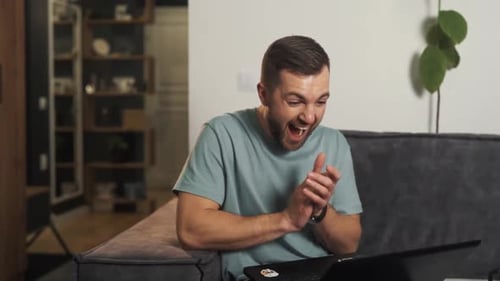 Man Celebrating Good News While Using Laptop Indoors