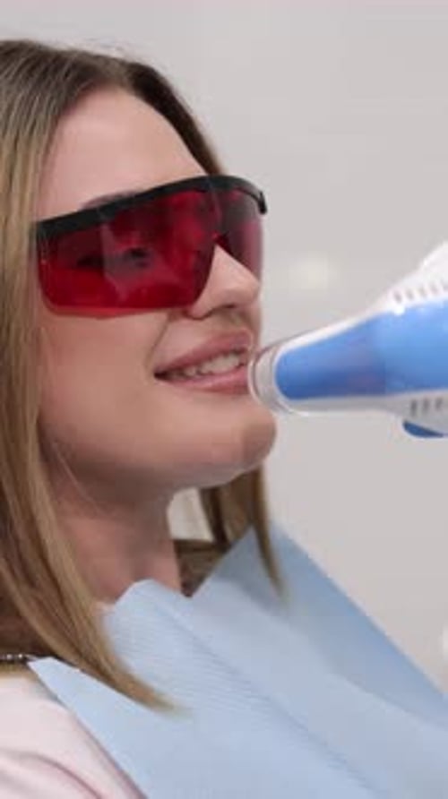 Woman Receiving Teeth Whitening Treatment at Dentist Office