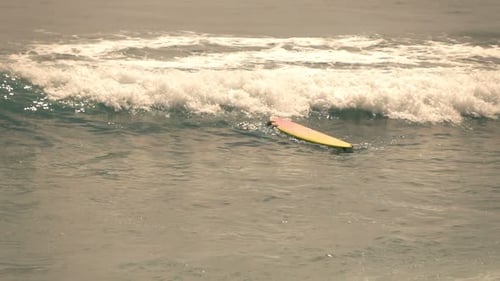 Man with surfboard submerges into the sea in super slow motion on summer vacations