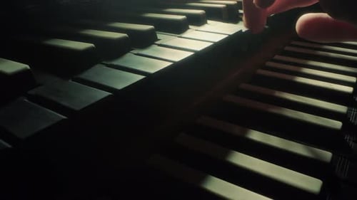 Fingers Play Piano Keys in Moody Lighting