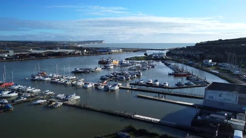 Wide angle establishing aerial shot small marina with boats moored to dock