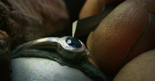 Slow motion macro of experienced goldsmith working on a handmade jewelry ring with precious gems i