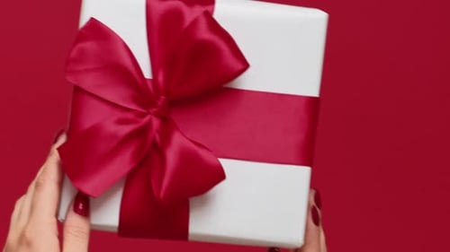 Hands Hold White Gift with Red Ribbon