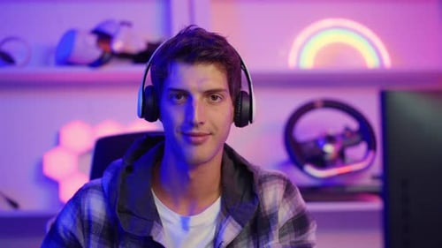 Young Man Puts on Headphones and Smiles