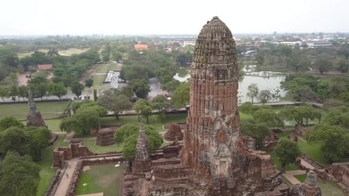 4K AERIAL ORBIT VIEW of buddhist temple in AYUTTHAYA, Thailand, with surrounding city and lake.