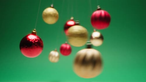 Mesmerizing Christmas Ball Pendulums Swing in Front of a Green Background