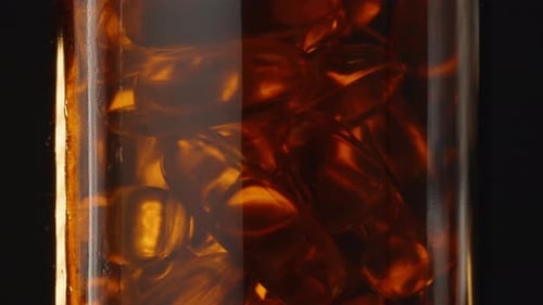 Amber Gel Capsules Rotating in a Clear Bottle