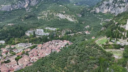 Camera pans over a small italian village nestled in a valley surrounded by lush green mountains
