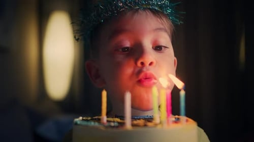 Boy in Party Hat Blows Out Birthday Candles