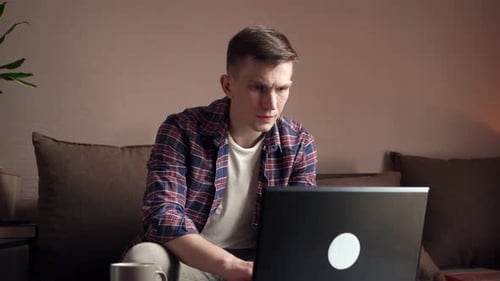 Young Man Works on Laptop at Home