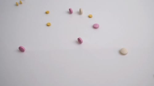 Medical Concept Pills Fall on a White Table
