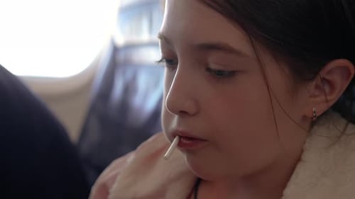 Young Girl Enjoying Lollipop While Traveling on Airplane During Sunny Day