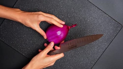 Woman cuts red onion on cutting board