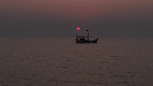serene wide shot of a traditional fishing boat floating on a calm sea at sunset