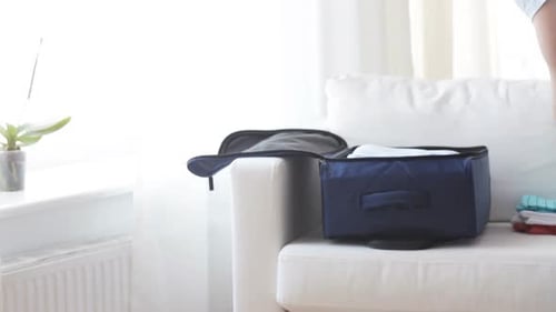 Man Packing Clothes in Blue Suitcase at Home