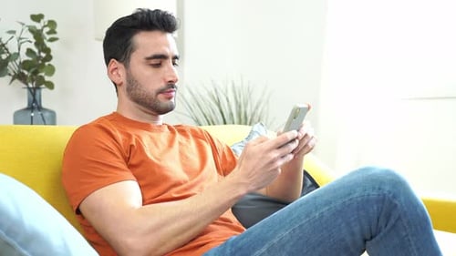 Man Relaxing on Couch While Using Smartphone