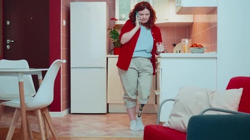 Woman with Prosthetic Leg Talking on Phone in Kitchen