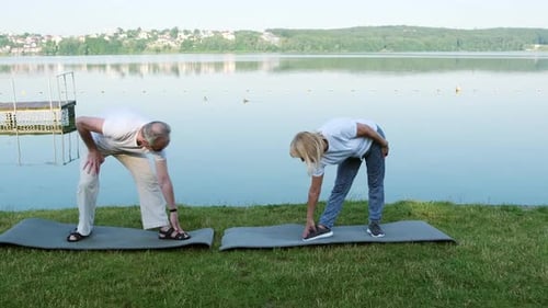 Active Senior Couple Stretching by a Calm Lake