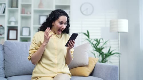 Woman Celebrates Good News on Smartphone at Home