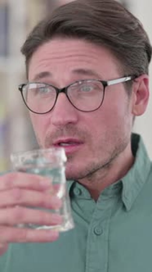 Mann mittleren Alters trinkt Wasser, vertikales Video