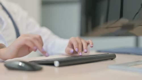 Nahaufnahme einer jungen Ärztin, die auf einem Desktop-Computer in der Klinik tippt
