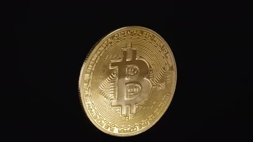 Goldene Bitcoin-Münze, die sich kontinuierlich in einer perfekten Schleife vor einem dunkelschwarzen Hintergrund dreht. Glatt