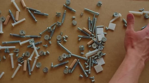 Composants de quincaillerie variés pour l'assemblage de meubles répartis sur une table Vue 4K