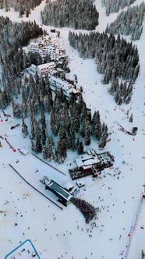 Aerial view of busy ski resort center with hotels and slopes in winter
