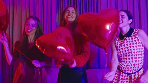 Three Women Dancing with Heart Balloons at a Party