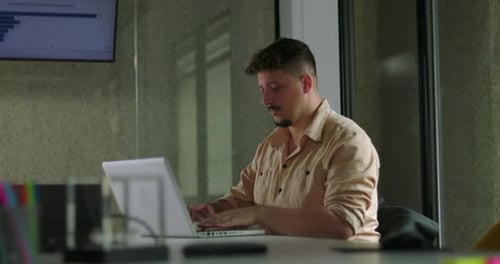 Male professional works on laptop with concentration at modern office desk during