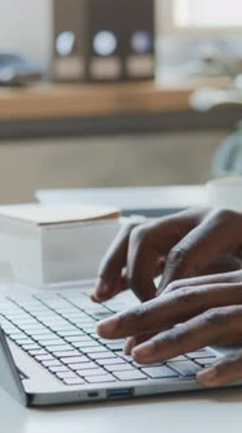 Vertikale der Hände eines schwarzen Geschäftsmannes, der im Büro am Laptop arbeitet