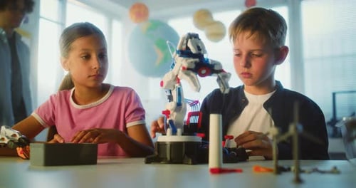 Primary School Children Sitting at Table Studying Robotic Arm Model