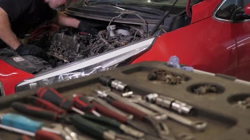 A Mechanic Repairing an Engine Under the Hood of a Car at a Service Station