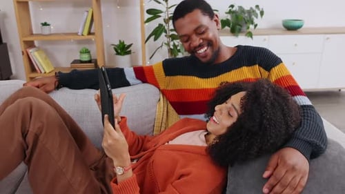 Relaxing Couple Looking at Tablet on Sofa
