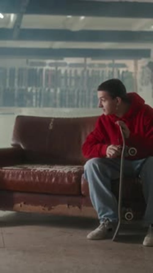 Young Skateboarder Fixing Deck and Greeting Friend with Indoor Skatepark