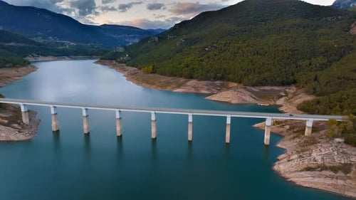 Aerial View of a Modern Bridge Over a Tranquil Lake in the Mountains