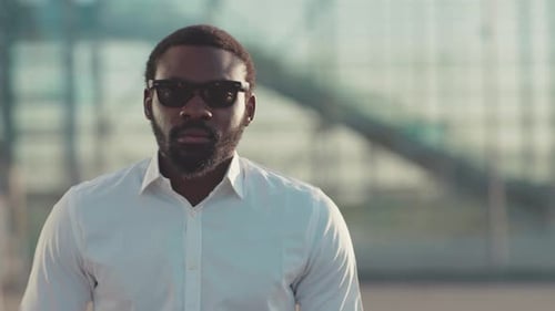 Man with Sunglasses Standing Outside in Urban Setting