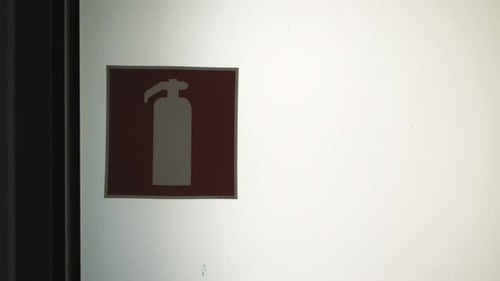 A Red Fire Extinguisher Sign Hangs on a White Wall